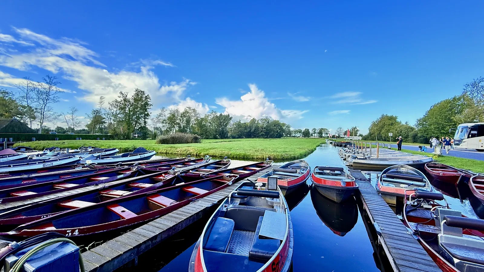 Houten huurboten afgemeerd aan steigers langs een rustig kanaal